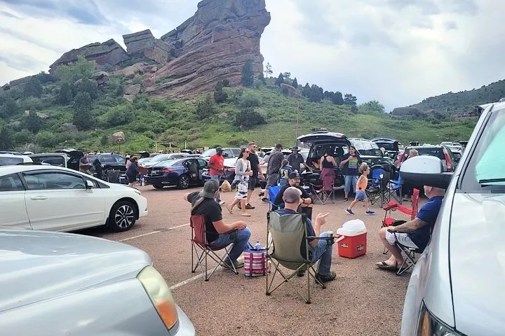 A group tailgating in the Red Rocks parking lot, backdropped by a large rock formation