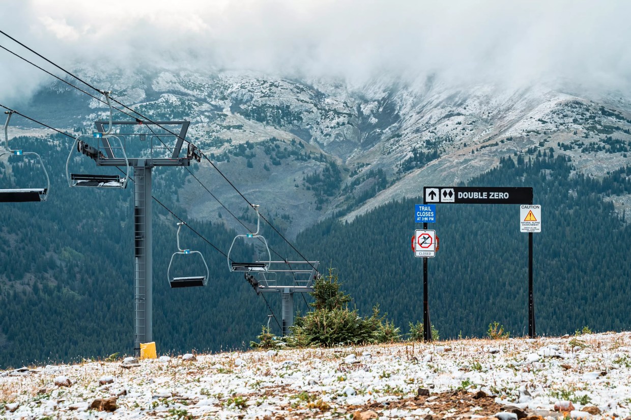 Ski hill with light snow in front of mountain peaks