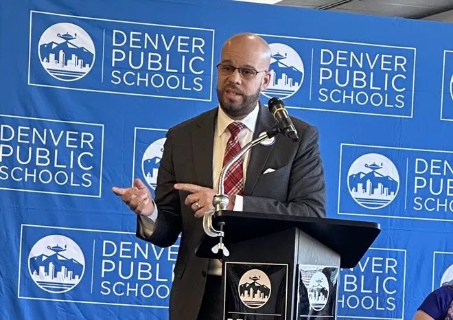 man at podium with school signs in background