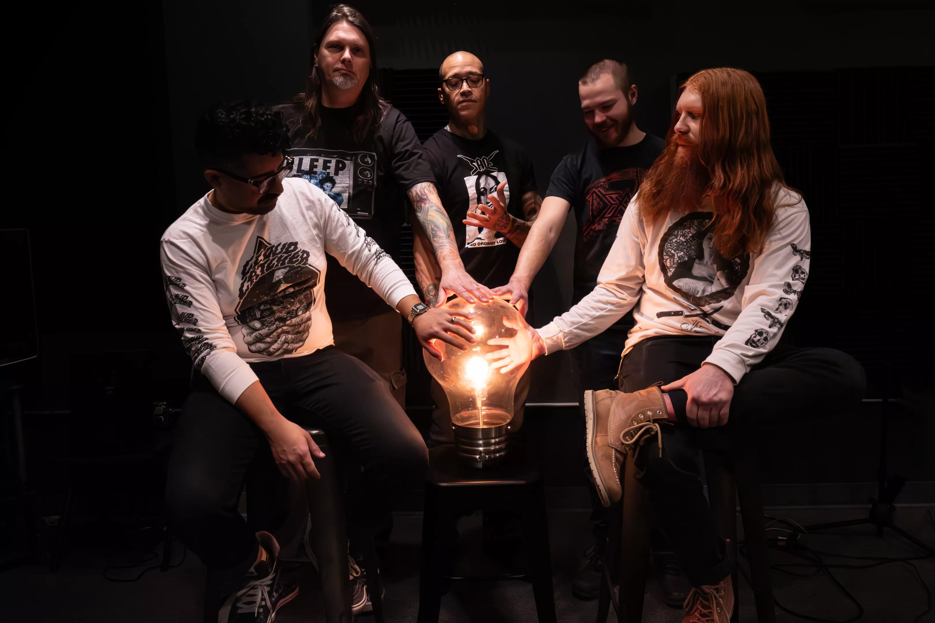 bandmembers gathered around a giant lightbulb