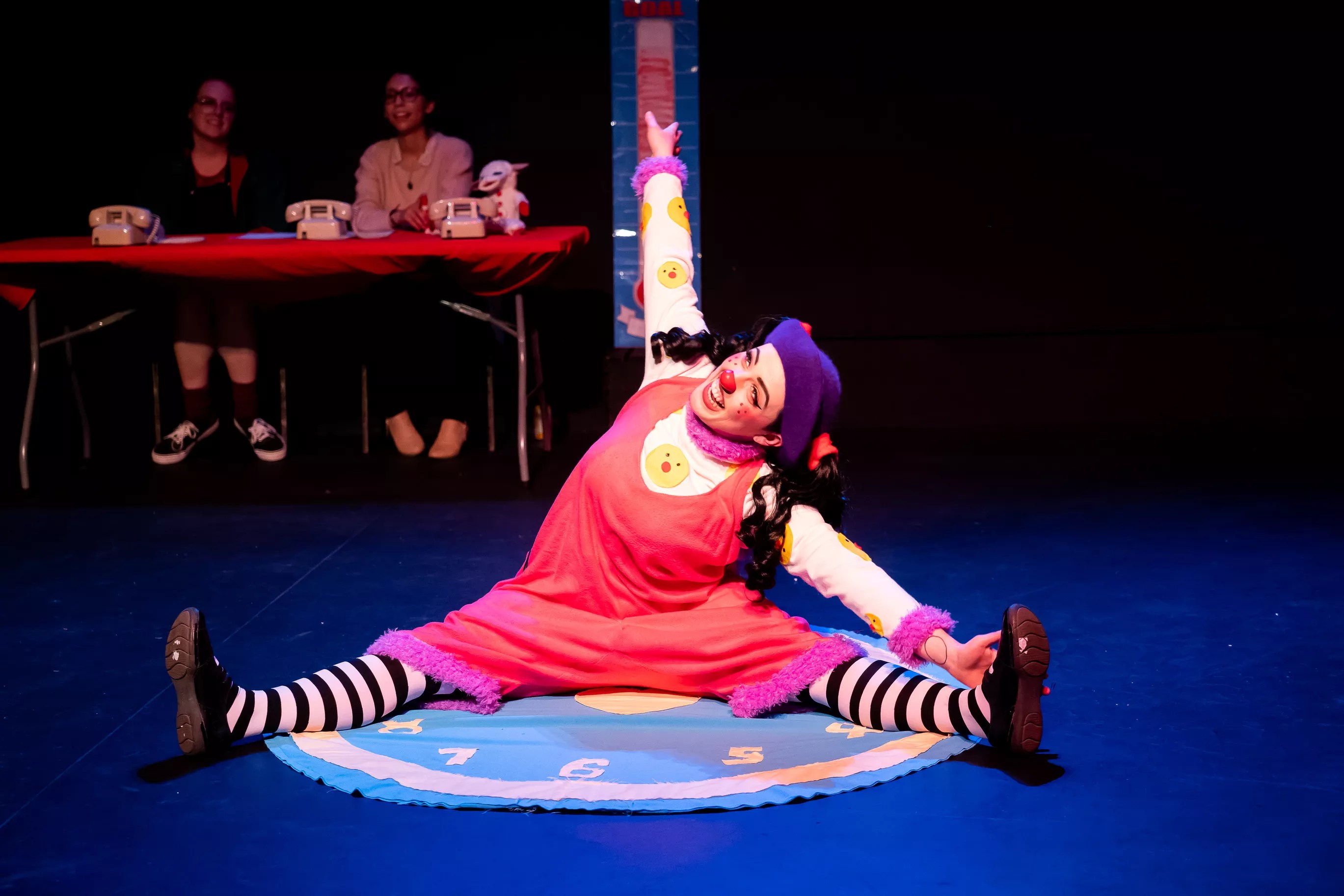 woman in tights and clown nose stretching on stage