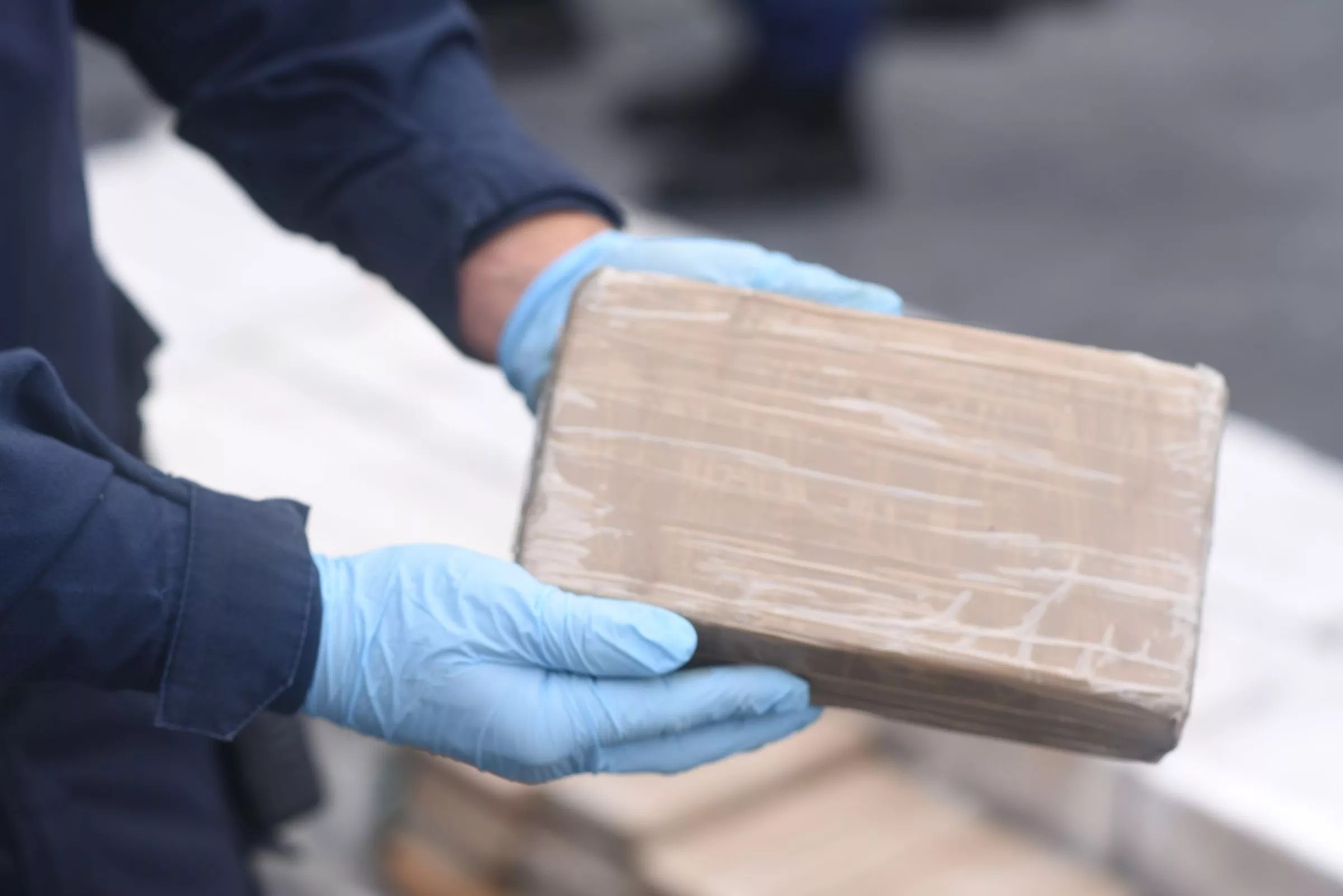 Crime scene investigator holds brick of seized cocaine