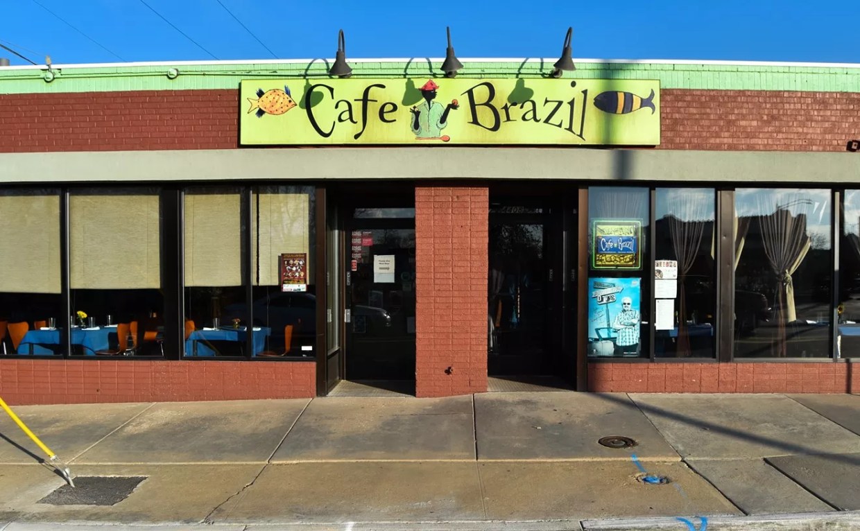 The brick exterior of Cafe Brazil featuring a green restaurant sign