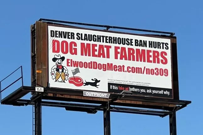A billboard reads, "Denver slaughterhouse ban hurts dog meat farmers, ElwoodDogMeat.com/no309" with illustrations of a wiener dog running from a piece of steak. At the bottom, it says, "If this fake ad bothers you, ask yourself why."