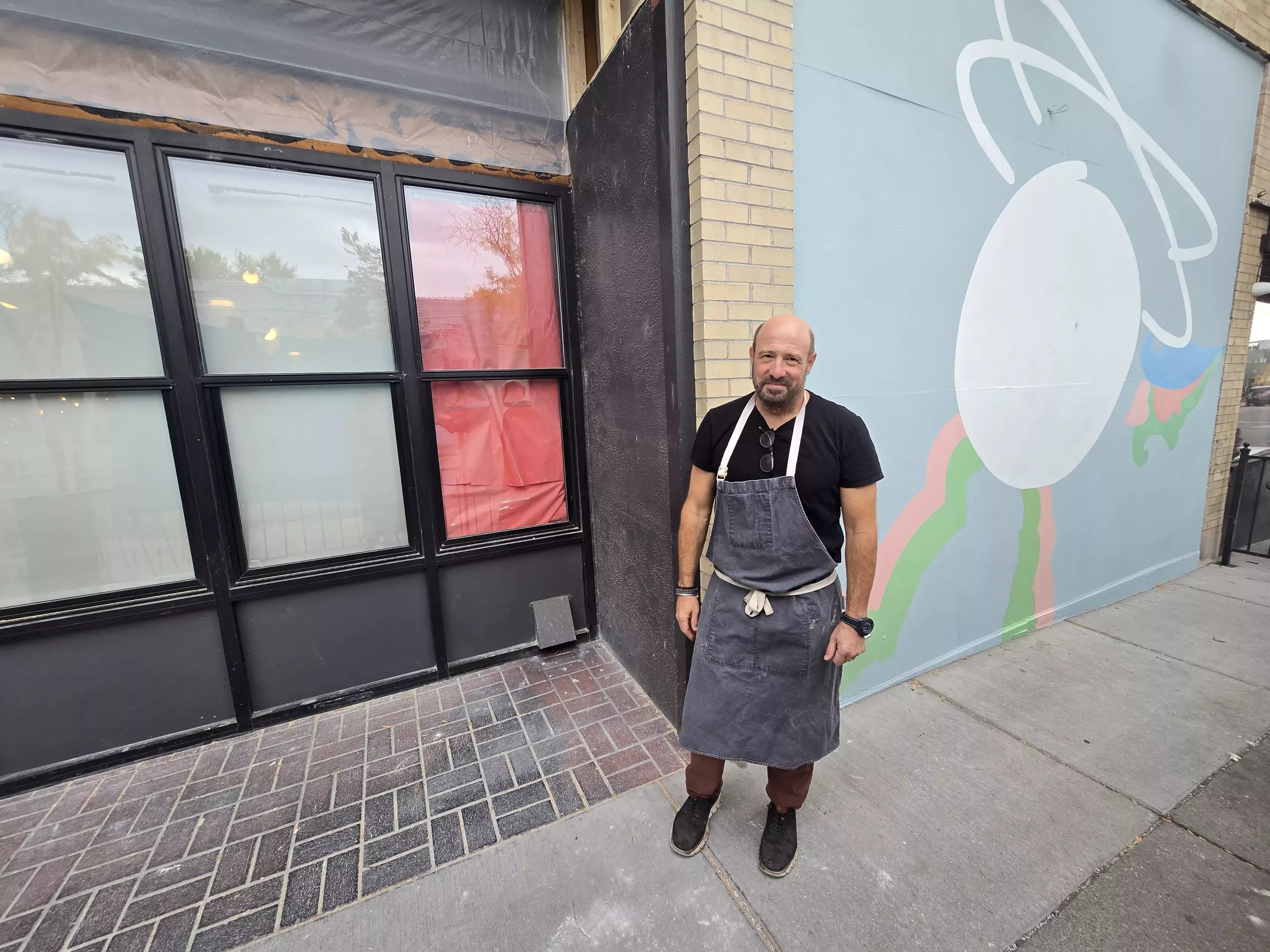 man in an apron standing in front of a building