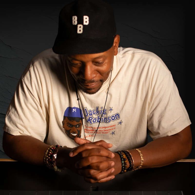 man in hat and t shirt looking down.