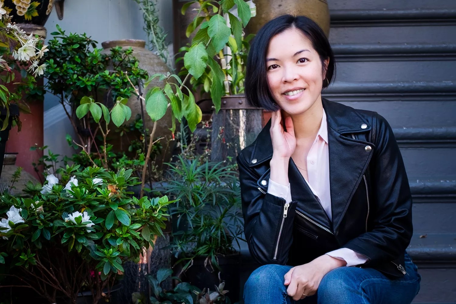 woman posing for a photo next to plants