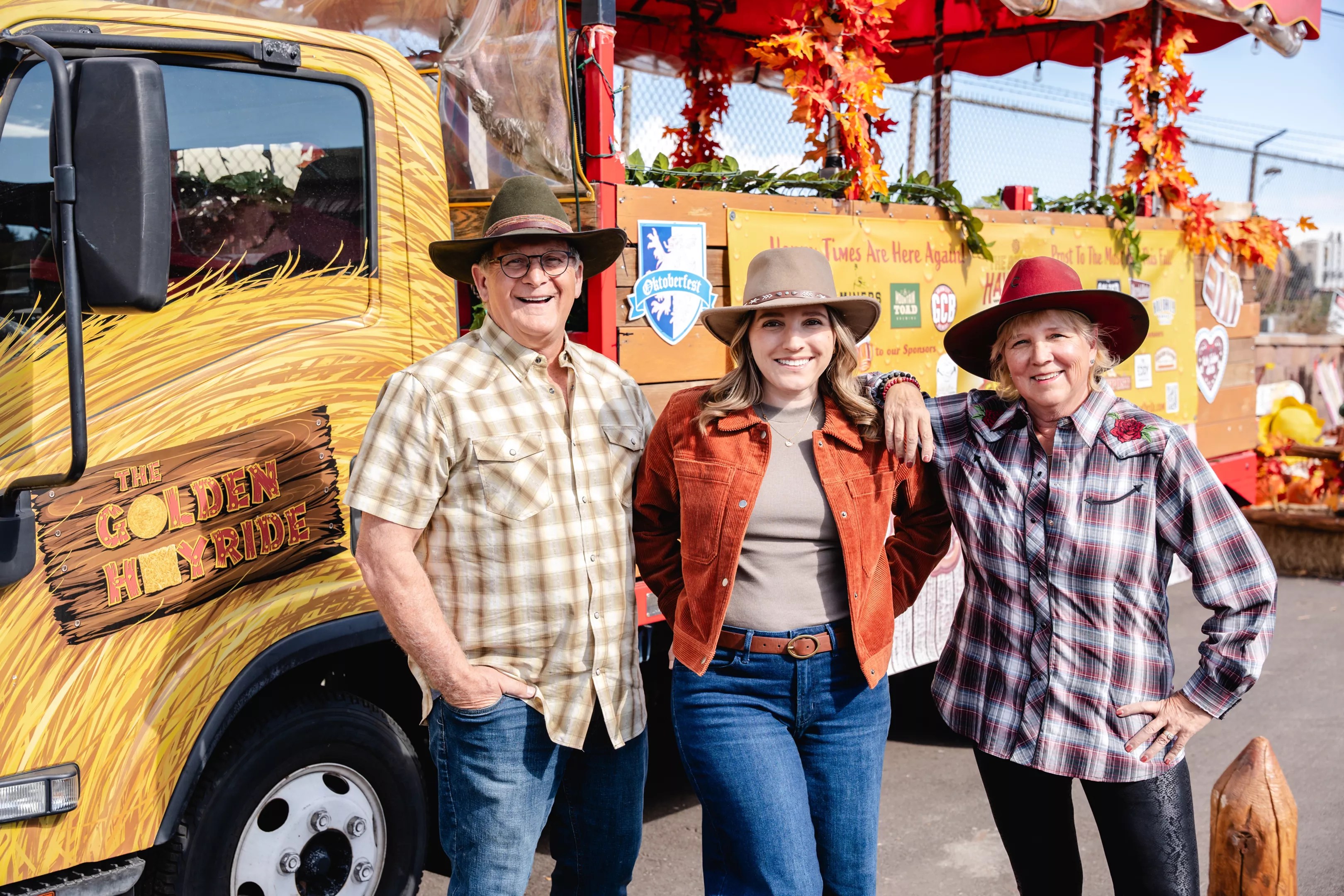 three people in western-style hats posing in front of a truck