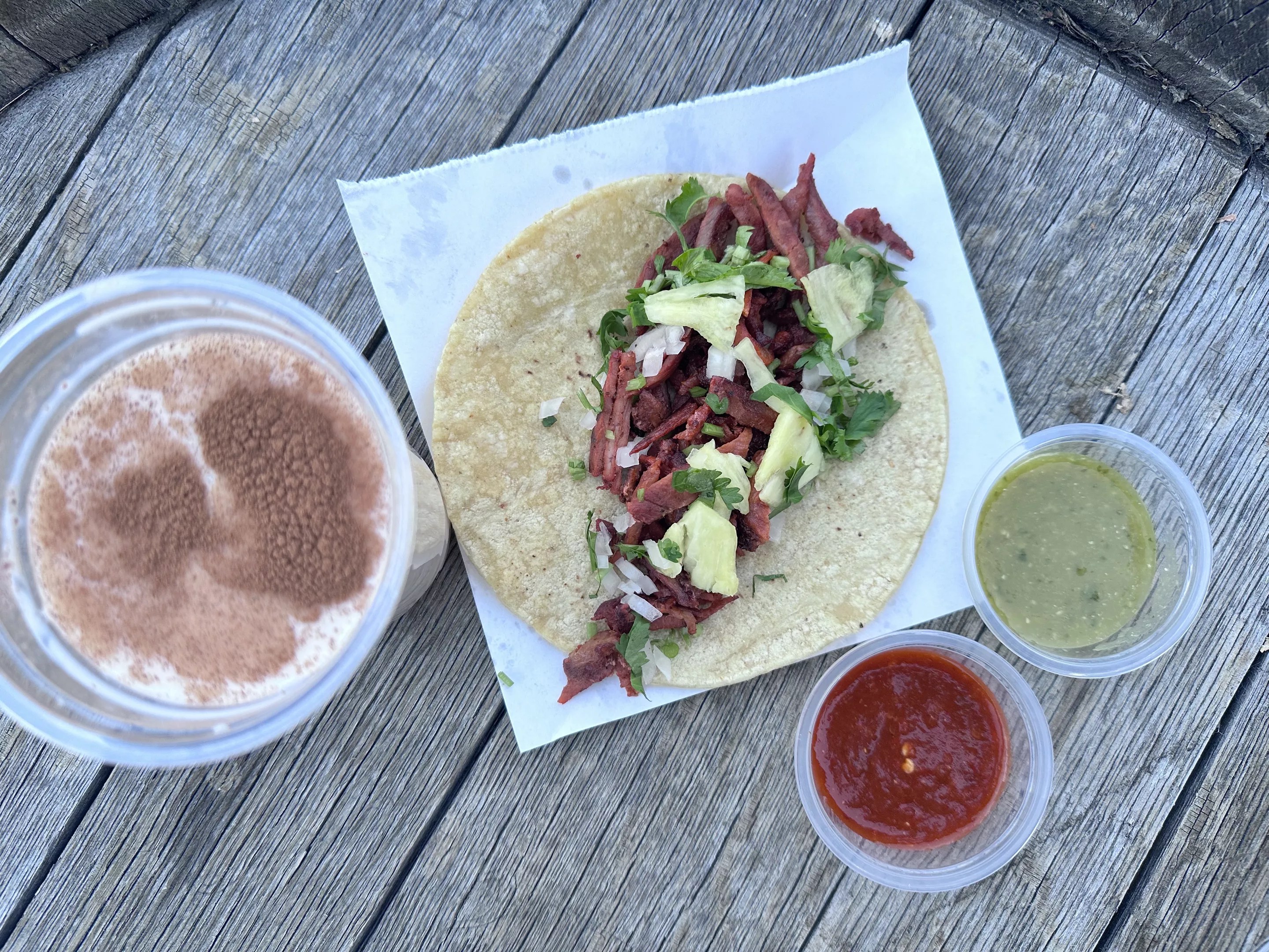 Traditional Al Pastor taco served with housemade red and green salsa and a cup of homemade horchata.
