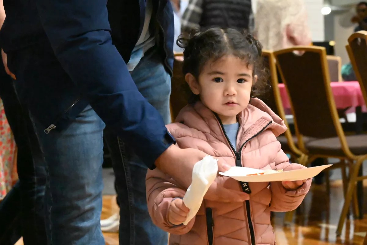 A little girl holds a plate.