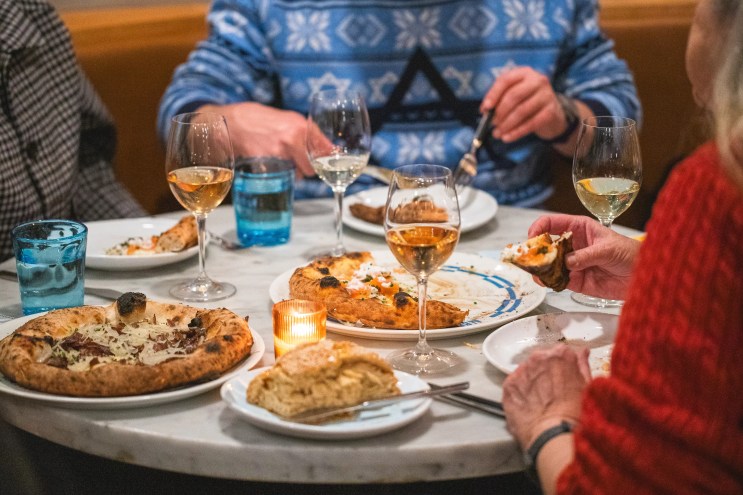 Three people enjoying wine and Neapolitan pizzas at Pizzeria Alberico
