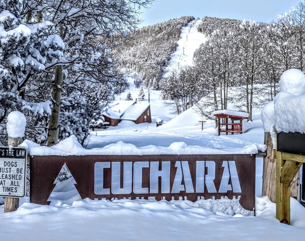 A large Cuchara Mountain Park sign backdropped by Baker Mountain ski slopes