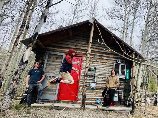 three men in front of cabin