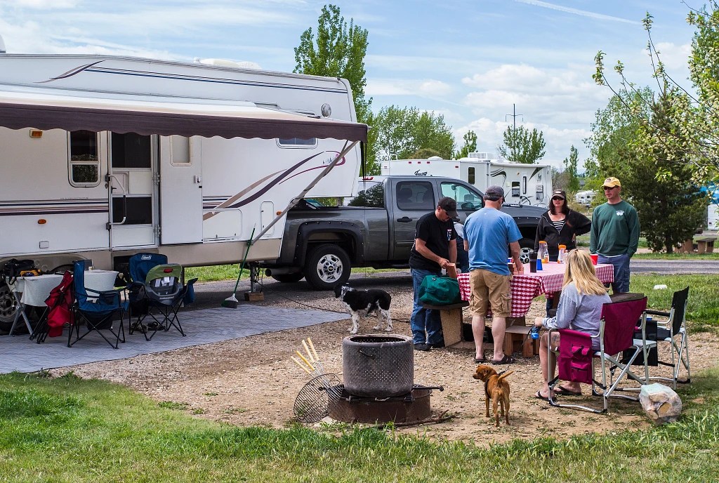 Campers eat at a picnic table near an RV