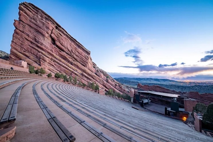 A sunrise view of the stage, empty stands and massive rock formation at Red Rocks Amphitheatre