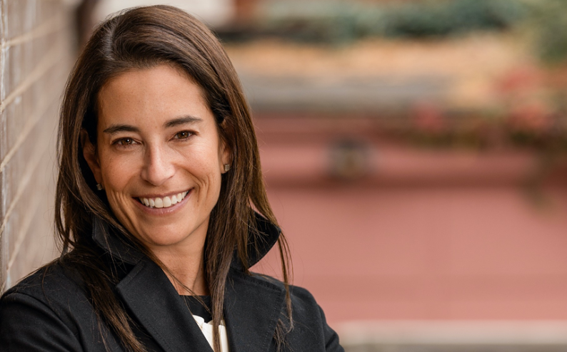 woman in black jacket, arms folded.