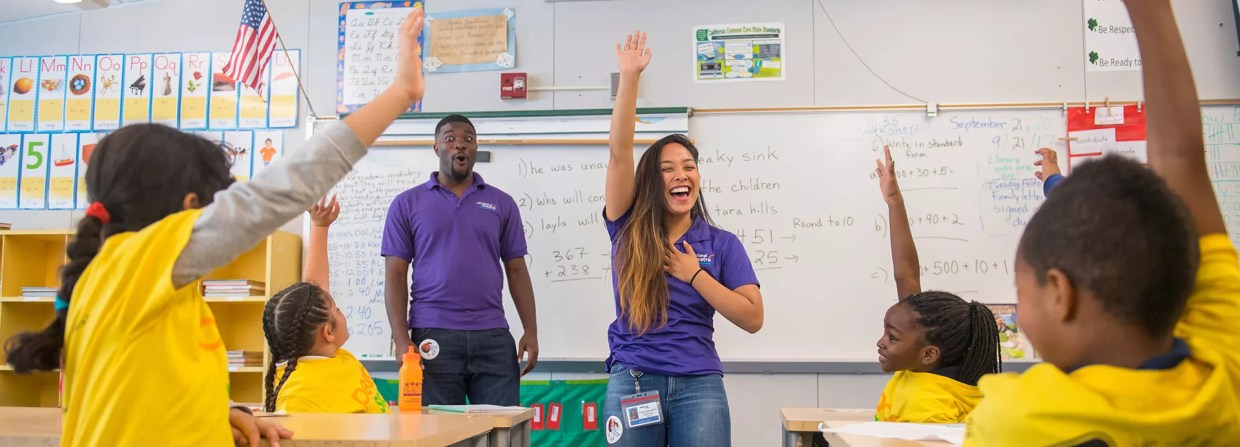 Teachers in a classroom speaking with students.