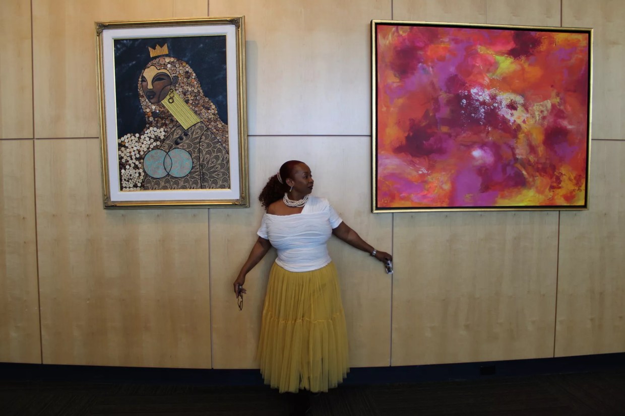 Black woman stands in front of two paintings.