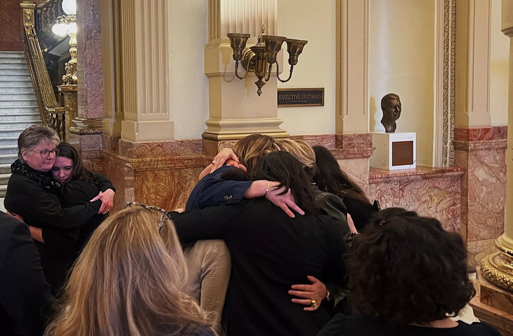 Women hug during legislative hearing