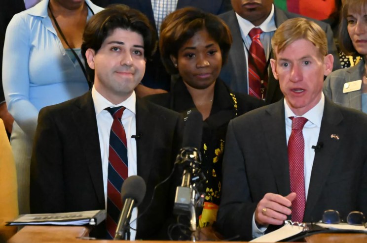 Two people speak at the Capitol.