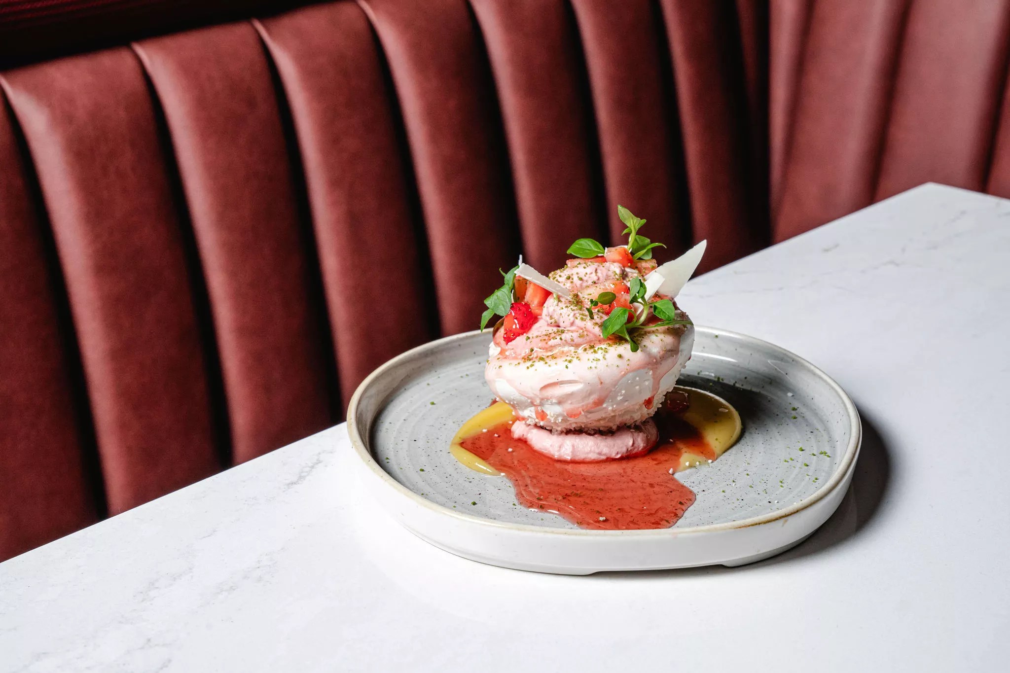 A coconut pavlova from Ajax, backdropped by a berry-colored booth