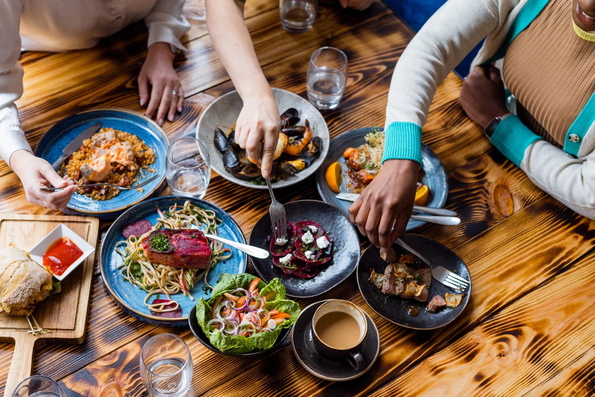 hands reaching for food on table