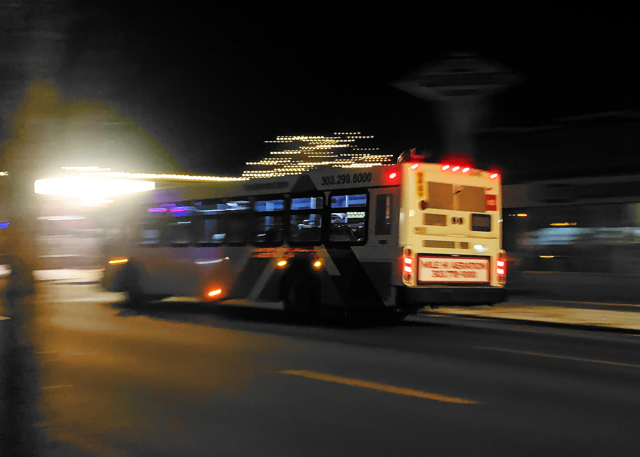 An RTD bus drives down a road at night