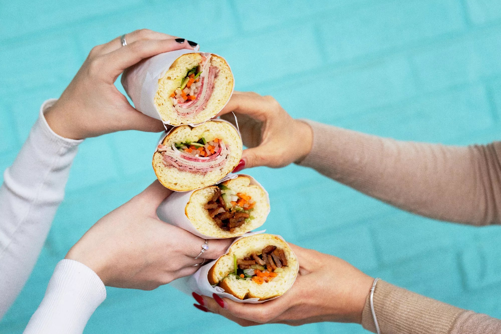 hands holding four bánh mì