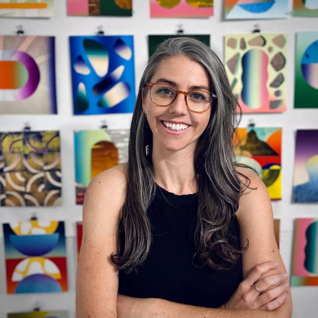 A woman sits in front of a wall of art
