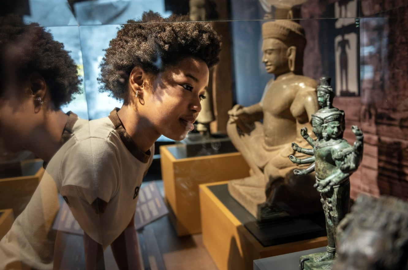 A boy looks at a small statue