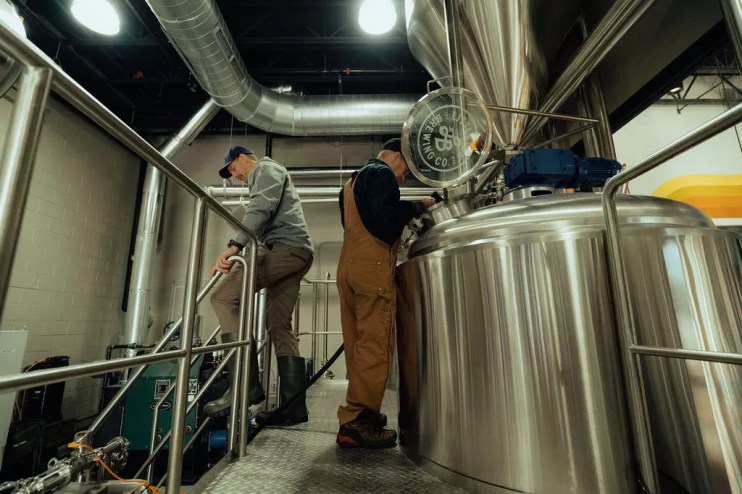 two men near brewing equipment.