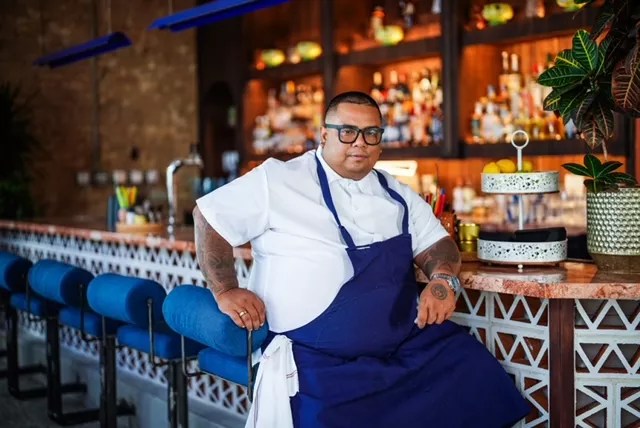 man in a white chef's coat and blue apron