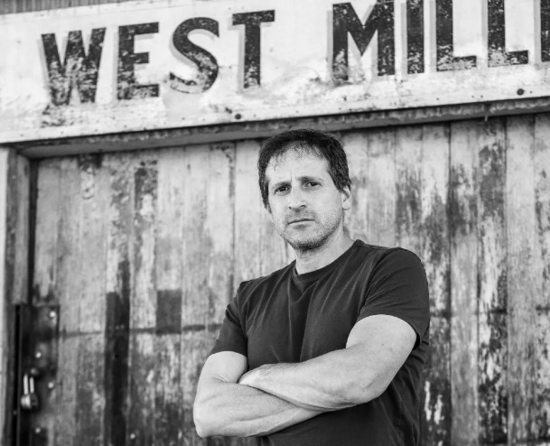 A black and white photo of a man with his arms crossed