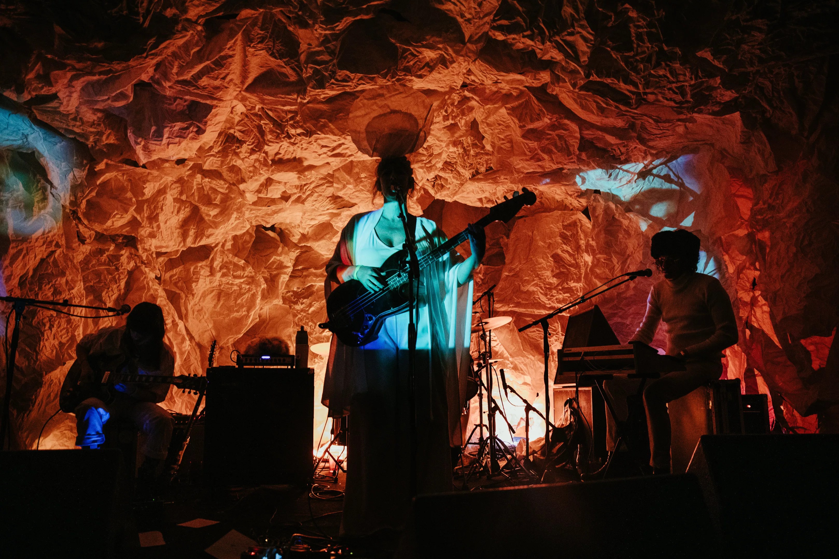 A band performs against an orange background.