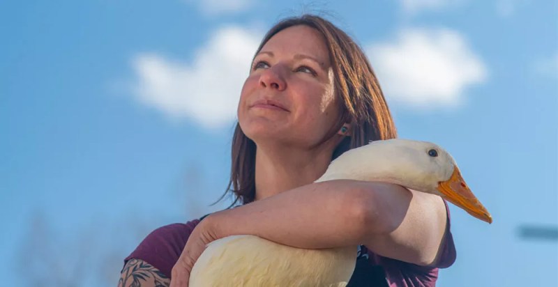 woman holding duck, looking at sky