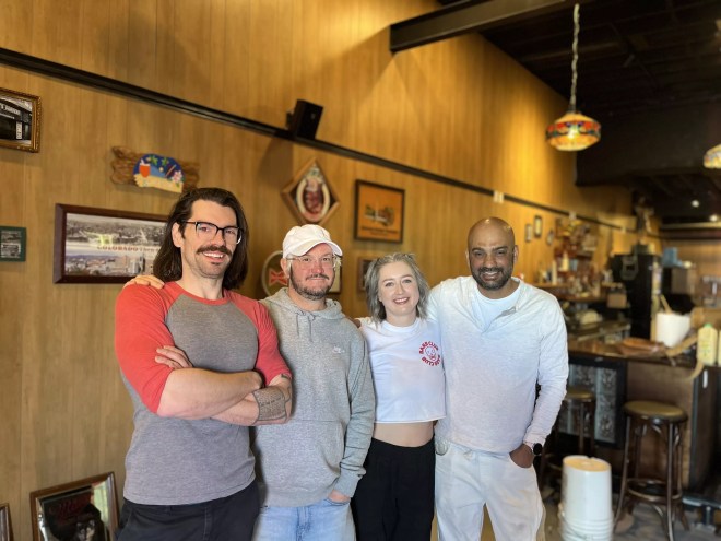 four people standing inside a bar