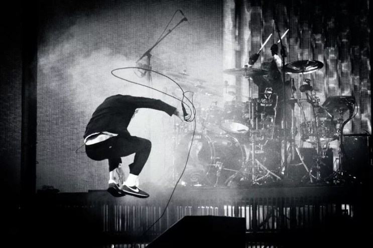 member of Deftones jumping on stage with a microphone