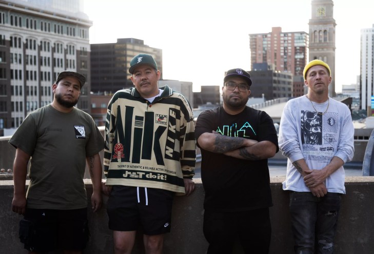 A group of men lean against a balcony.