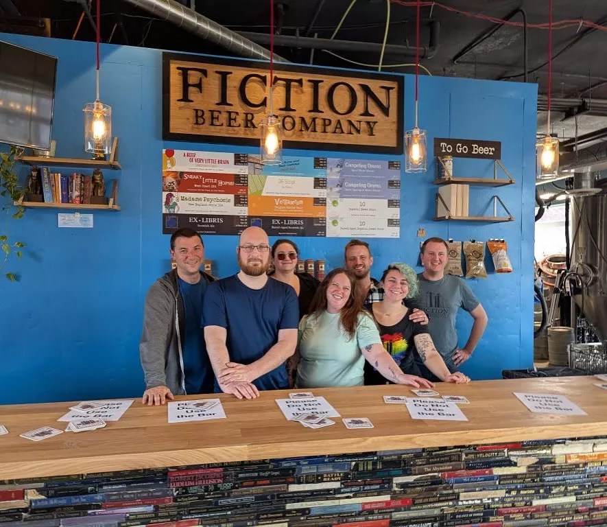 Owners standing behind bar of brewery.