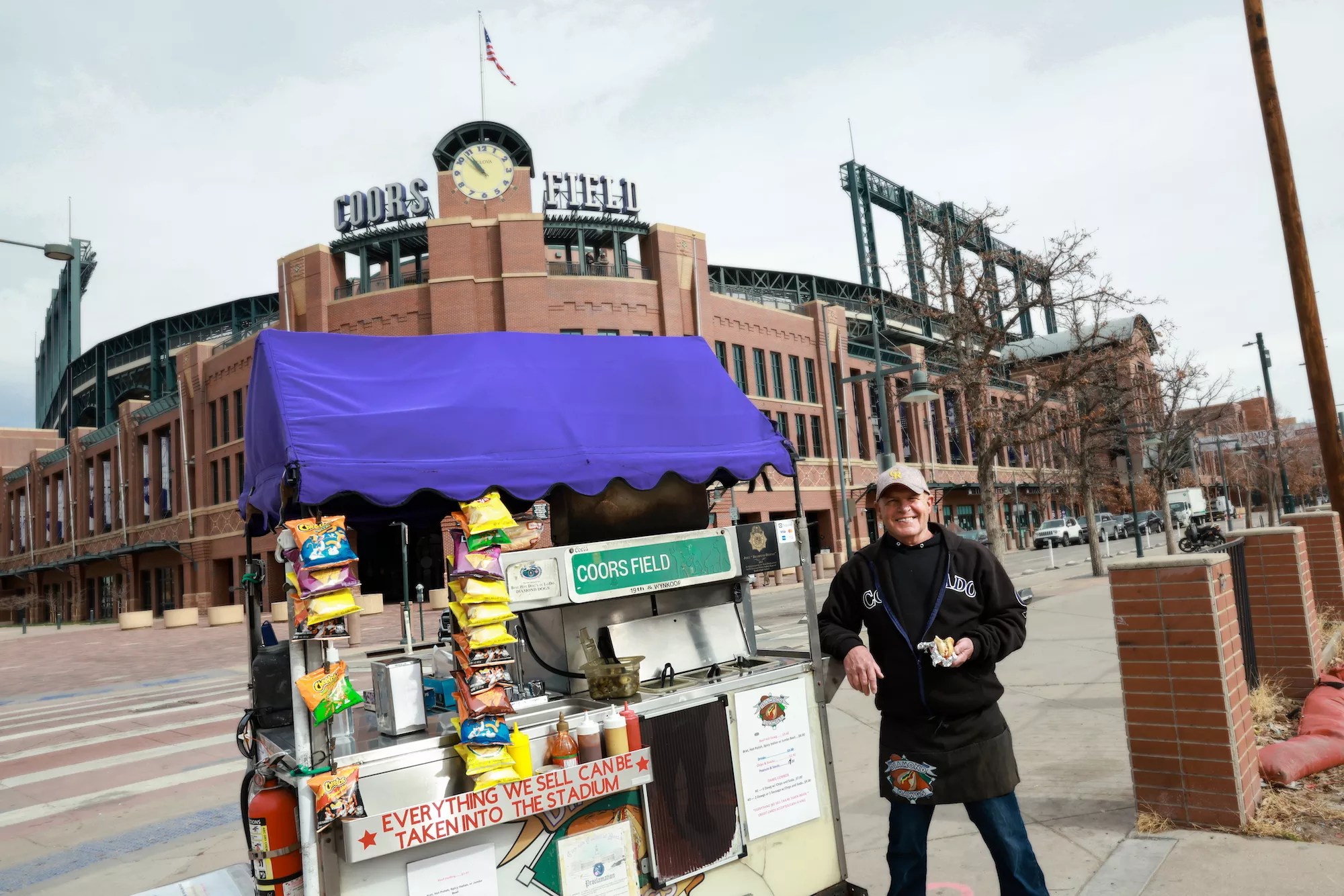 man standing next to a hot dog cart