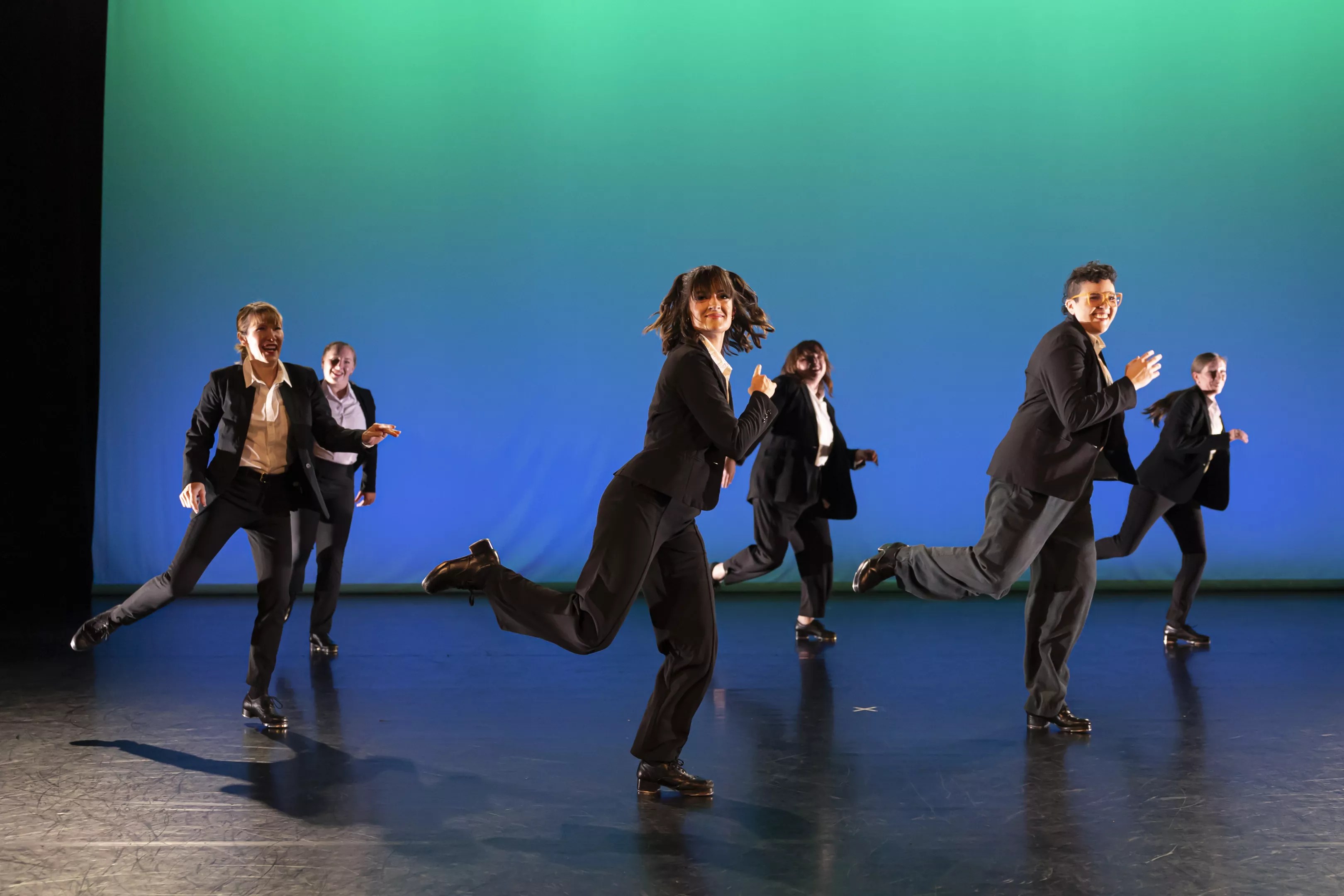 A group of people tap dance onstage.