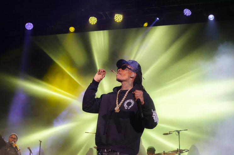 A photo of Wiz Khalifa on stage at Red Rocks smoking a joint.