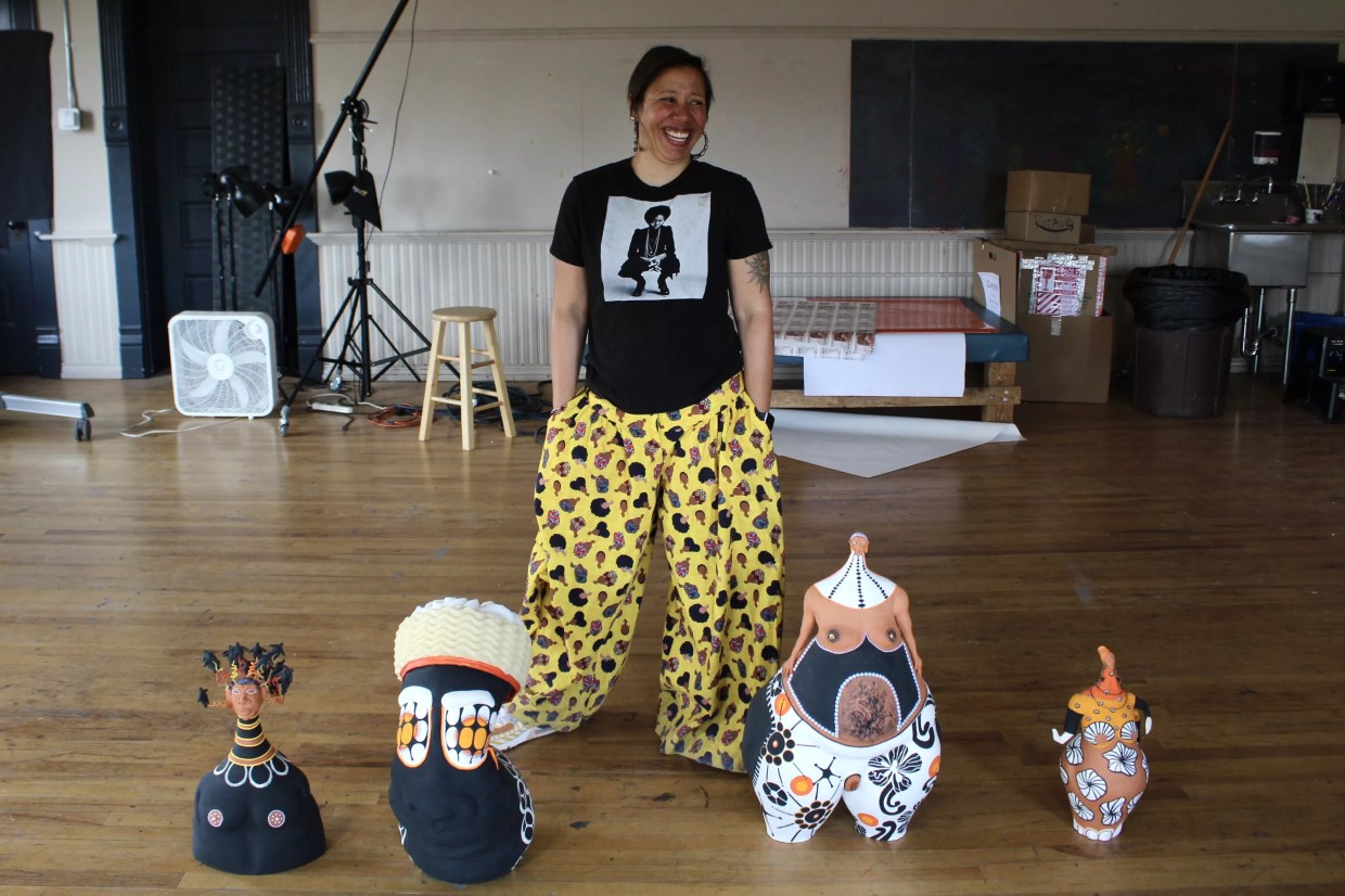 A woman stands with clay figurines