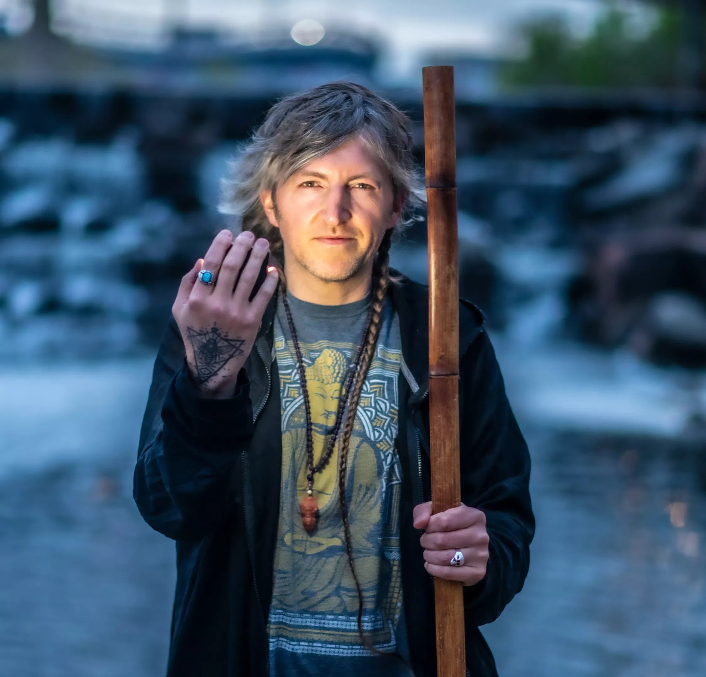 man by river with stick and hand up