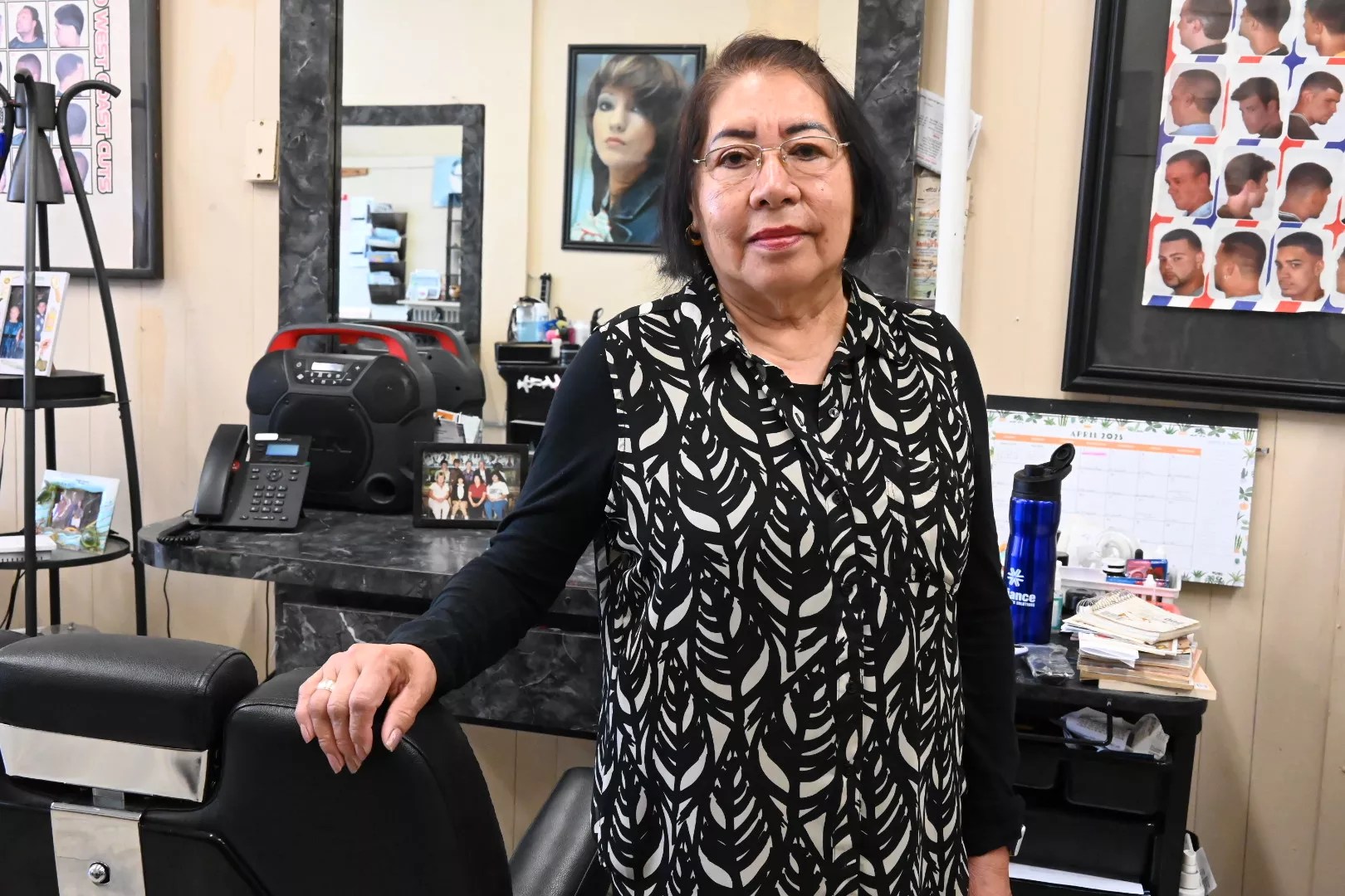 A barber stands by her chair.
