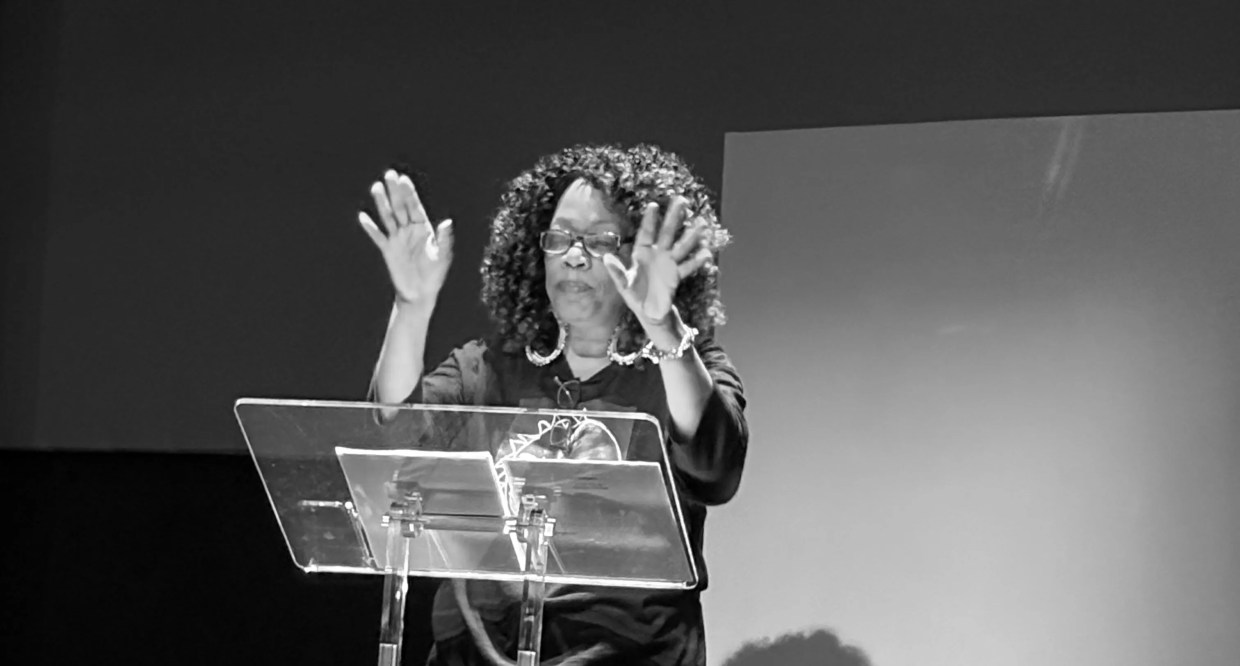 A Black woman stands behind a podium.