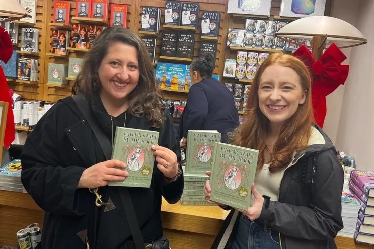 two women hold up books