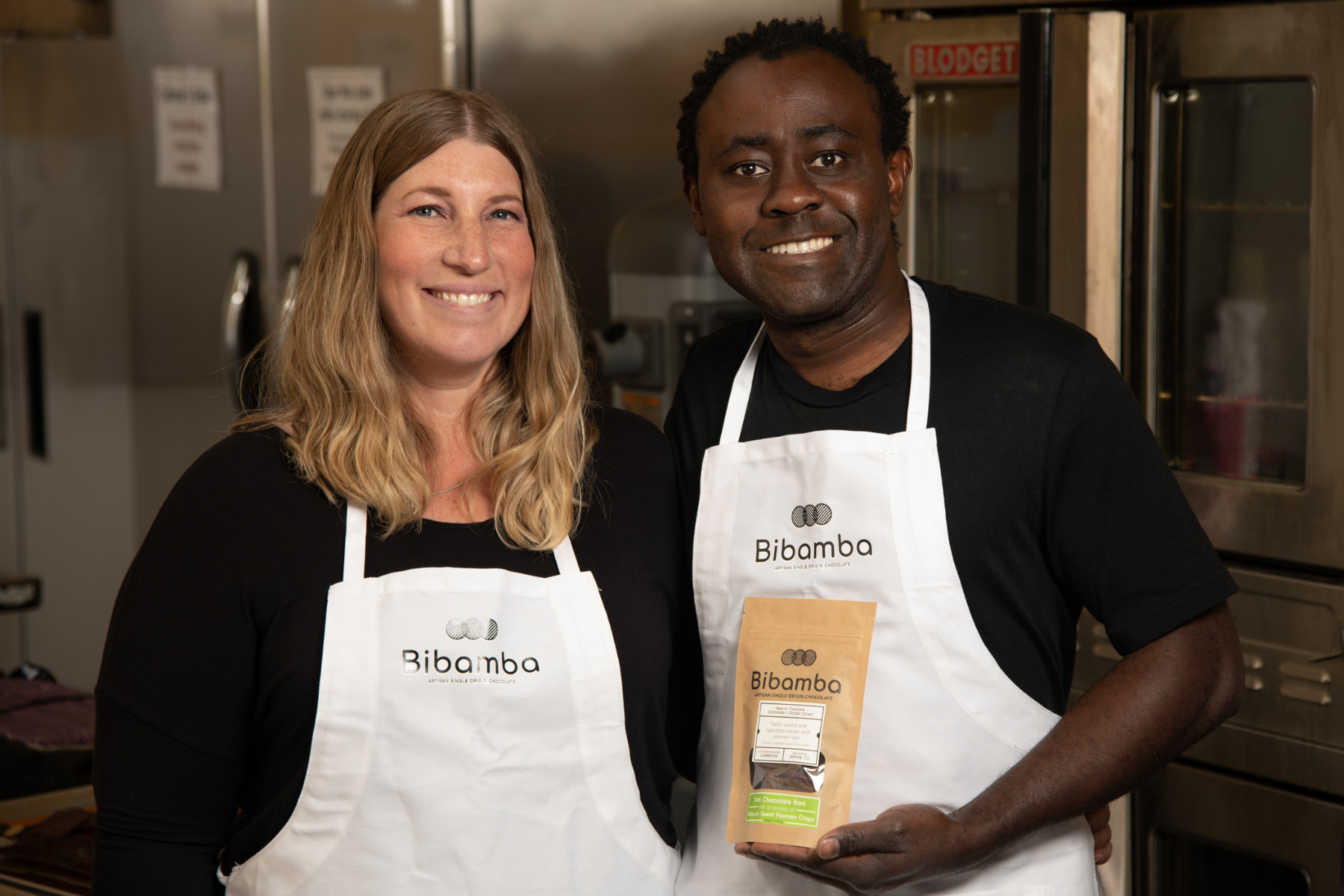 Mara and Patrick Tcheunou wearing white aprons in their chocolate kitchen