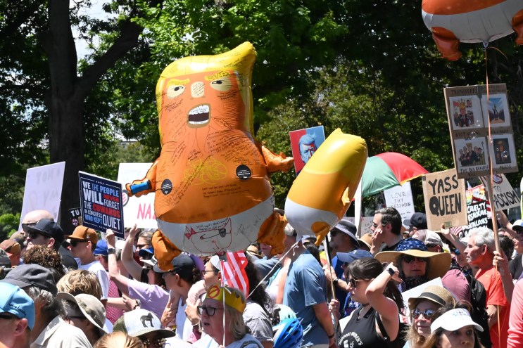 woman holds orange trump baby balloon at protest