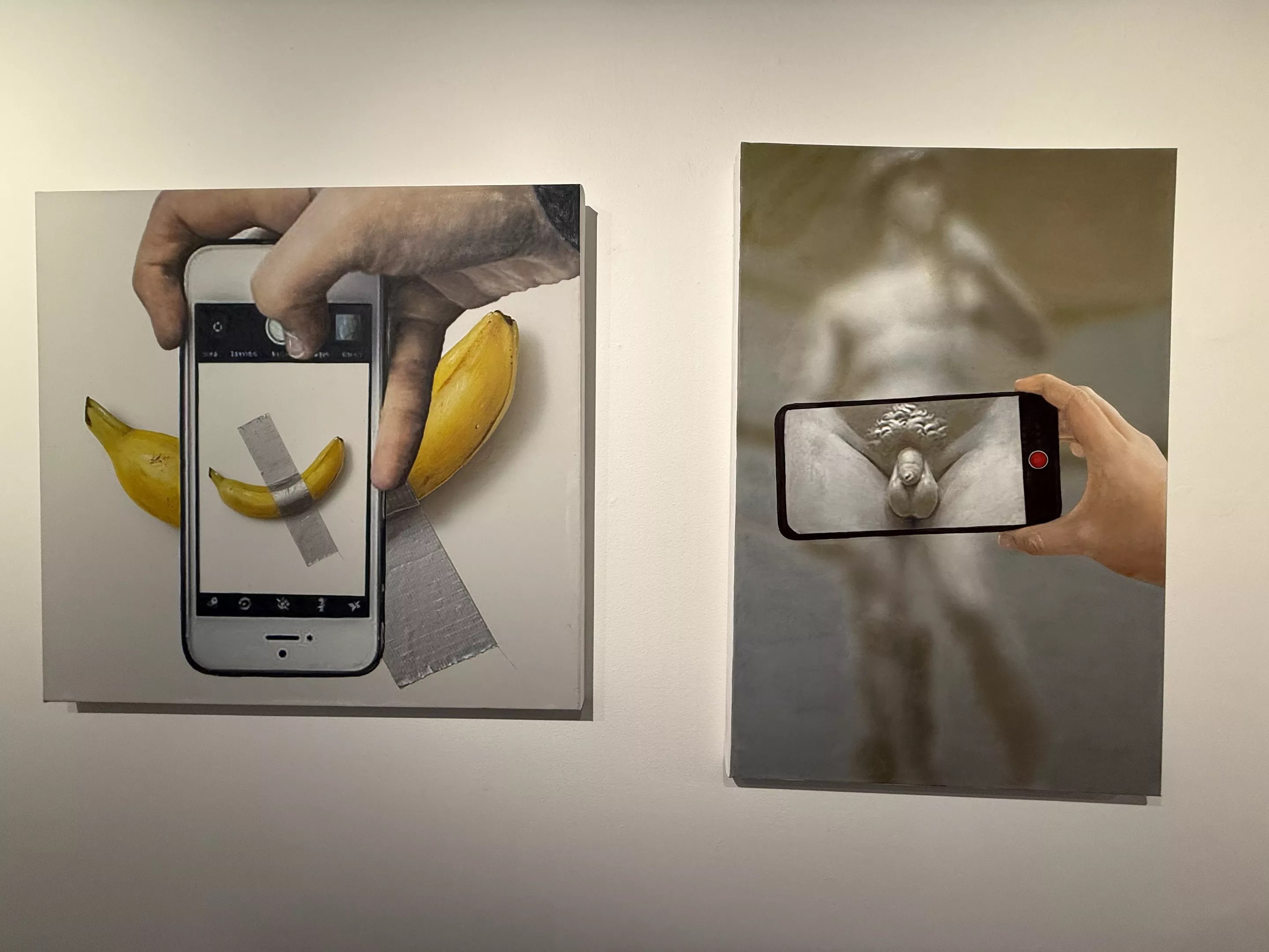 Two pieces of art that showcase someone taking a photo of a banana duct-taped to the wall and someone taking a photo of a male statue's genitals.